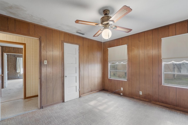 unfurnished bedroom with ceiling fan and wooden walls