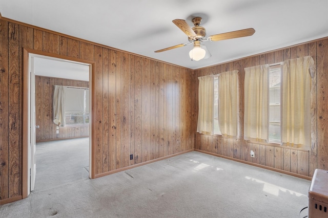 spare room with light carpet, ceiling fan, and wooden walls