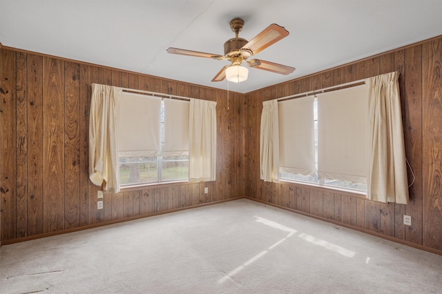 carpeted spare room featuring ceiling fan and wooden walls