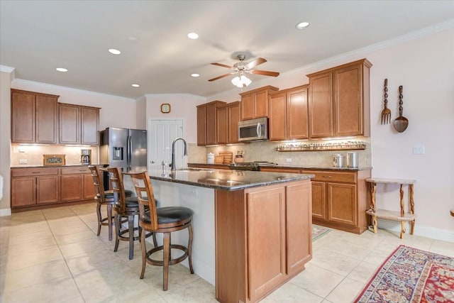 kitchen with appliances with stainless steel finishes, sink, a breakfast bar area, a kitchen island with sink, and light tile patterned floors