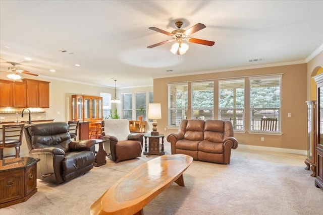 living area with light carpet, visible vents, baseboards, ceiling fan, and ornamental molding