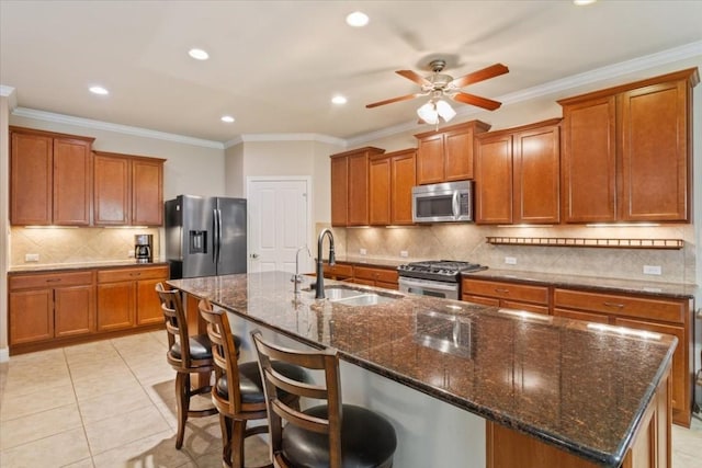 kitchen with brown cabinets, a breakfast bar area, stainless steel appliances, a kitchen island with sink, and a sink