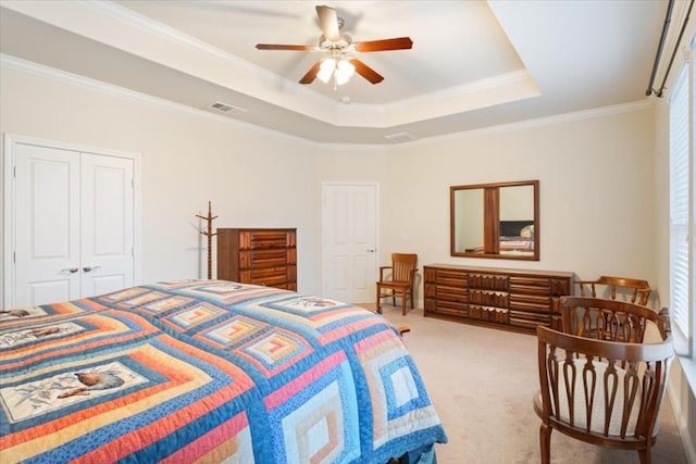 carpeted bedroom featuring visible vents, a ceiling fan, ornamental molding, a tray ceiling, and a closet