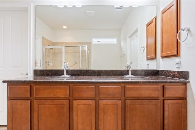 full bathroom with double vanity, a shower stall, and a sink