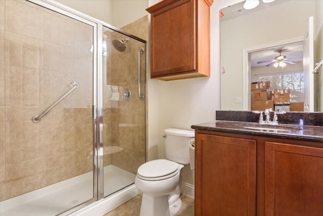 bathroom with ceiling fan, vanity, a shower stall, and toilet