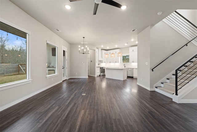 unfurnished living room with ceiling fan with notable chandelier and dark hardwood / wood-style floors