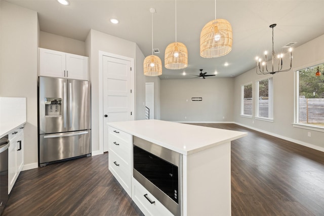 kitchen with decorative light fixtures, a center island, stainless steel appliances, white cabinets, and ceiling fan with notable chandelier