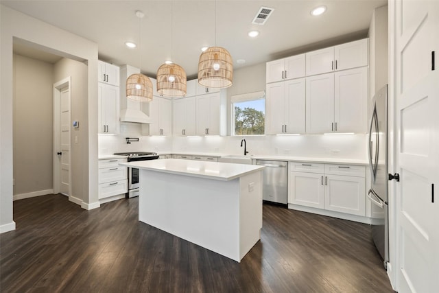 kitchen with decorative light fixtures, white cabinets, appliances with stainless steel finishes, and a center island