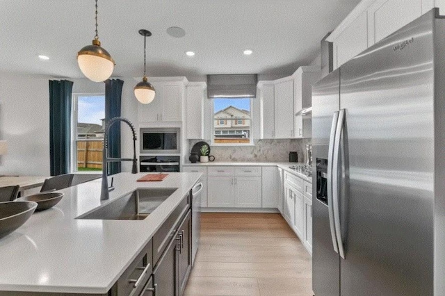 kitchen featuring stainless steel fridge with ice dispenser, pendant lighting, white cabinets, and sink