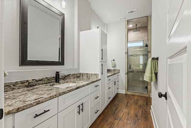 bathroom with a shower with shower door, wood-type flooring, and vanity