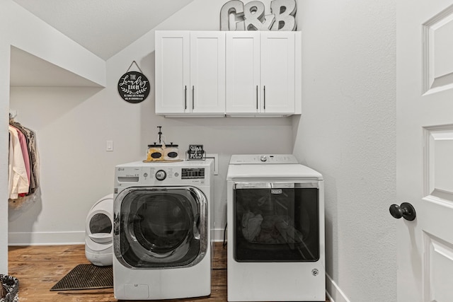 laundry room with cabinets, hardwood / wood-style floors, and washer and clothes dryer