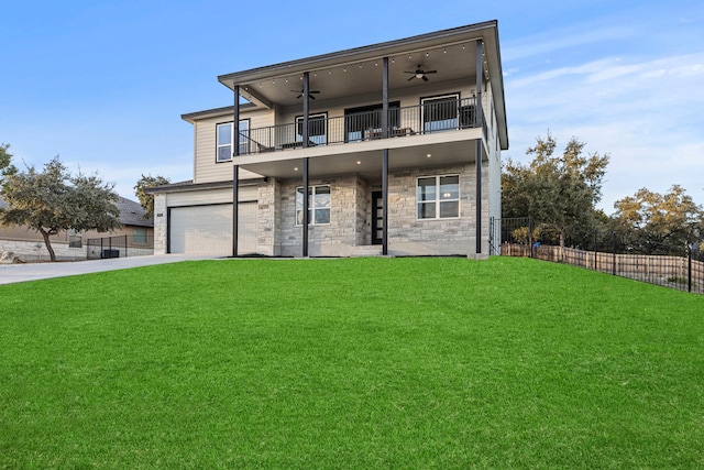 back of property with ceiling fan, a balcony, a yard, and a garage