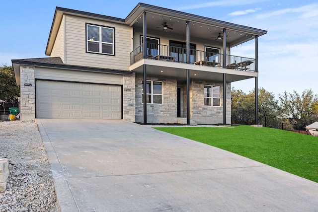 view of front of house with ceiling fan, a garage, a balcony, and a front yard