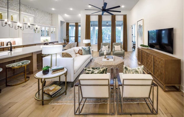 living room with ceiling fan with notable chandelier and light hardwood / wood-style flooring