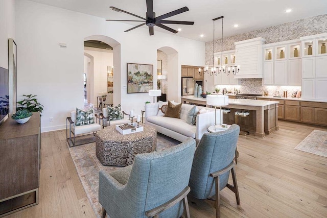 living room featuring light wood-type flooring and ceiling fan with notable chandelier