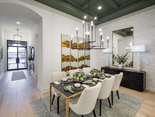 dining area featuring light hardwood / wood-style floors, coffered ceiling, french doors, a chandelier, and beam ceiling