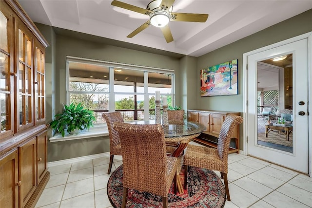 dining space with ceiling fan, a raised ceiling, and light tile patterned floors