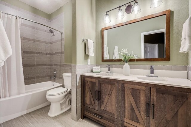 full bathroom with toilet, tile walls, tile patterned floors, shower / tub combo, and vanity