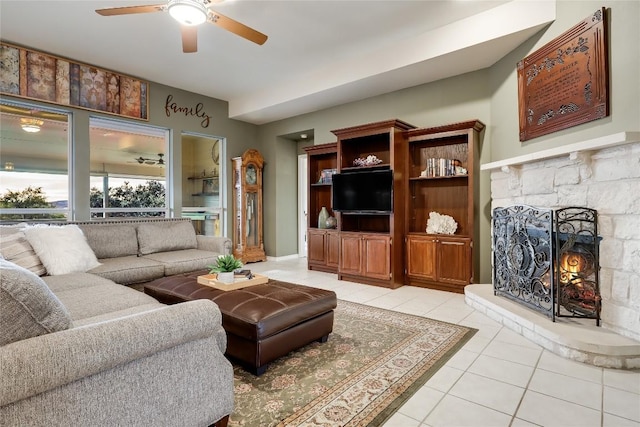 tiled living room with a stone fireplace and ceiling fan