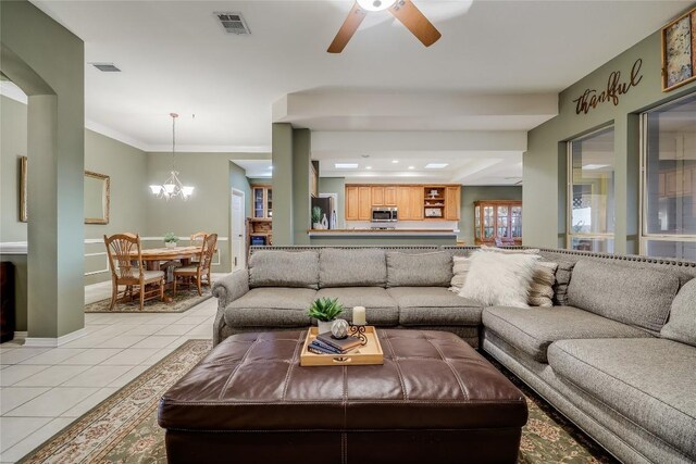 tiled living room with crown molding and ceiling fan with notable chandelier