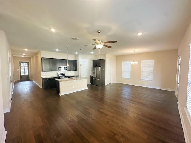 kitchen with a center island with sink, stainless steel appliances, dark hardwood / wood-style floors, pendant lighting, and ceiling fan with notable chandelier