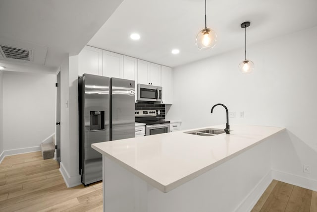 kitchen featuring sink, hanging light fixtures, appliances with stainless steel finishes, and kitchen peninsula