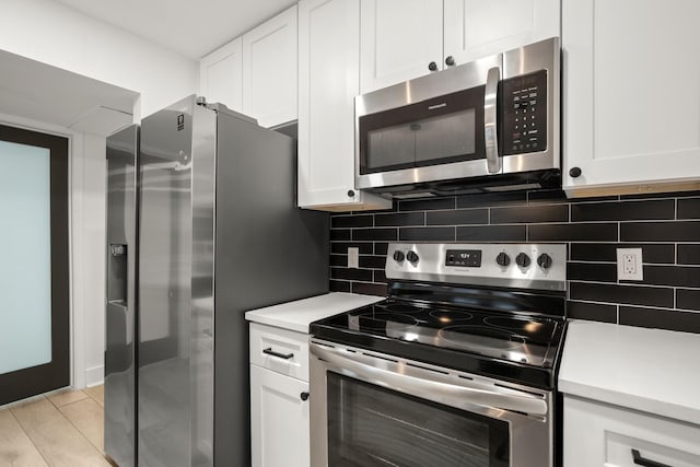 kitchen with backsplash, white cabinetry, appliances with stainless steel finishes, and light wood-type flooring