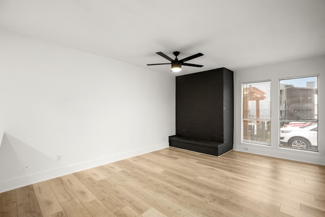 unfurnished living room featuring ceiling fan, a brick fireplace, and light hardwood / wood-style floors