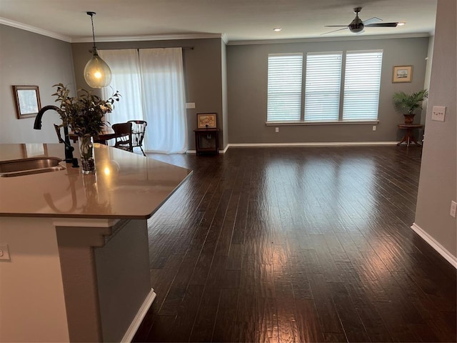 unfurnished dining area featuring ceiling fan, dark wood-type flooring, sink, and ornamental molding