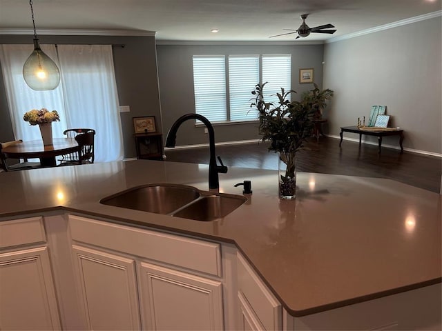 kitchen with ceiling fan, white cabinetry, crown molding, and sink