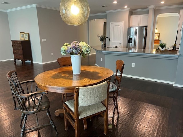 dining room with dark hardwood / wood-style floors, sink, and ornamental molding