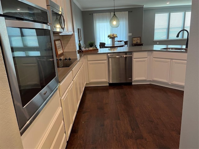 kitchen with kitchen peninsula, stainless steel appliances, backsplash, decorative light fixtures, and sink