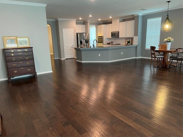 kitchen featuring appliances with stainless steel finishes, backsplash, dark wood-type flooring, hanging light fixtures, and white cabinets