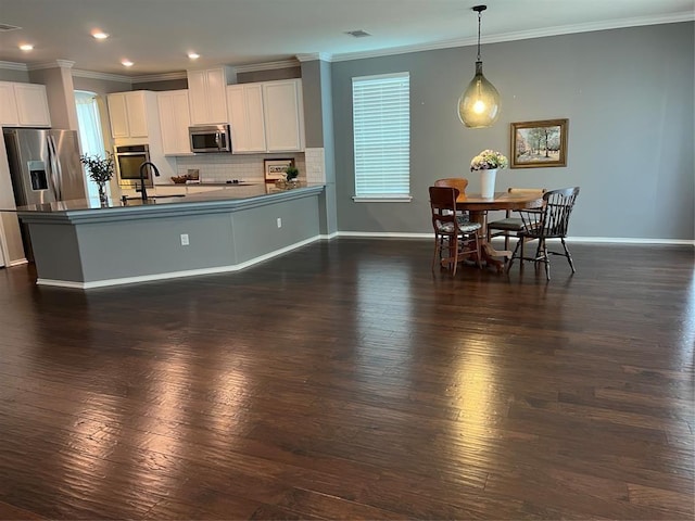 kitchen with pendant lighting, white cabinets, stainless steel appliances, and tasteful backsplash