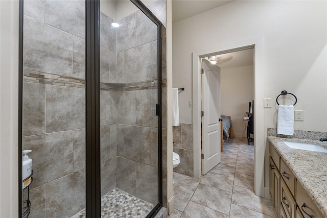 bathroom featuring toilet, tile patterned flooring, a shower with door, and vanity