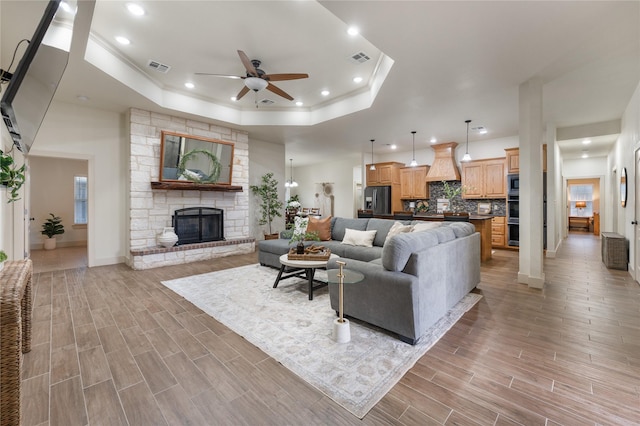 living room with ceiling fan, a fireplace, and a raised ceiling