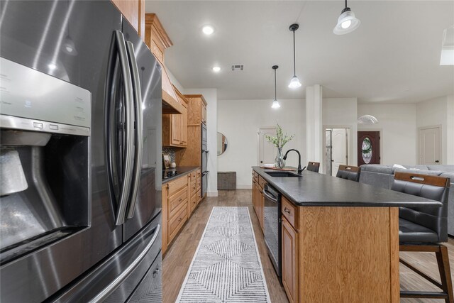 kitchen with pendant lighting, dishwasher, stainless steel refrigerator with ice dispenser, sink, and light wood-type flooring