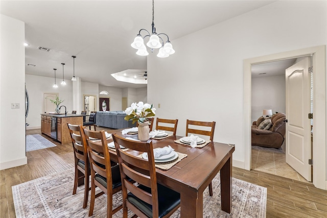 dining space featuring sink and ceiling fan with notable chandelier