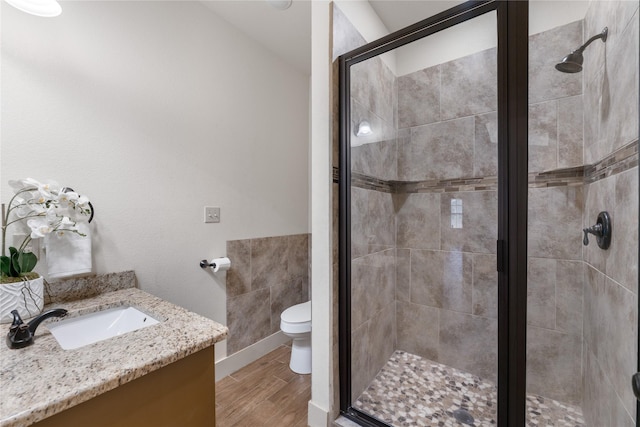 bathroom with a shower with shower door, tile walls, toilet, and vanity