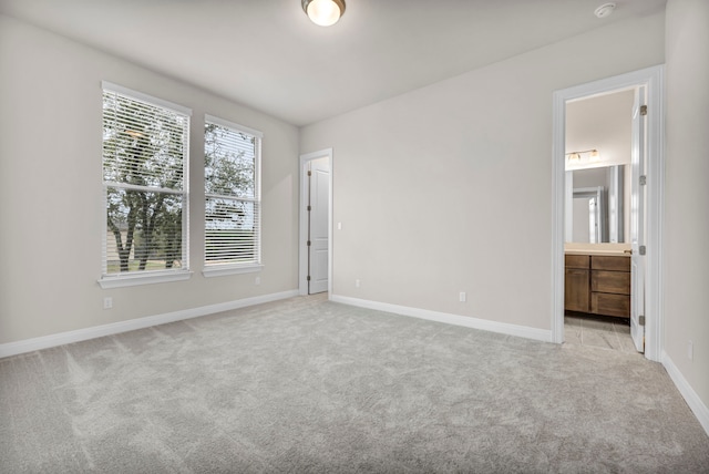 unfurnished bedroom with connected bathroom and light carpet