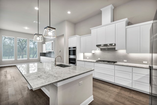 kitchen featuring white cabinetry, stainless steel appliances, sink, hanging light fixtures, and a kitchen island with sink