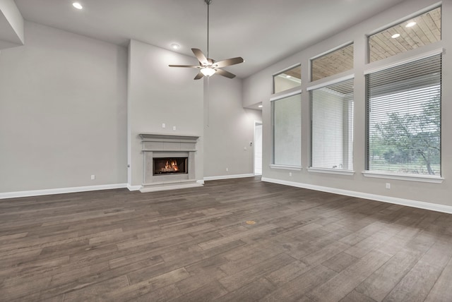 unfurnished living room with ceiling fan, dark wood-type flooring, and a towering ceiling