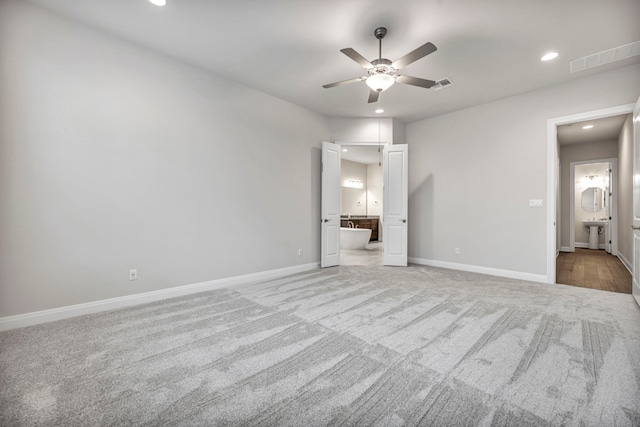 unfurnished bedroom featuring ceiling fan, sink, light carpet, and ensuite bath