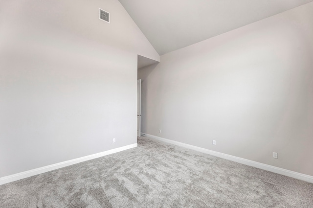 carpeted spare room with vaulted ceiling