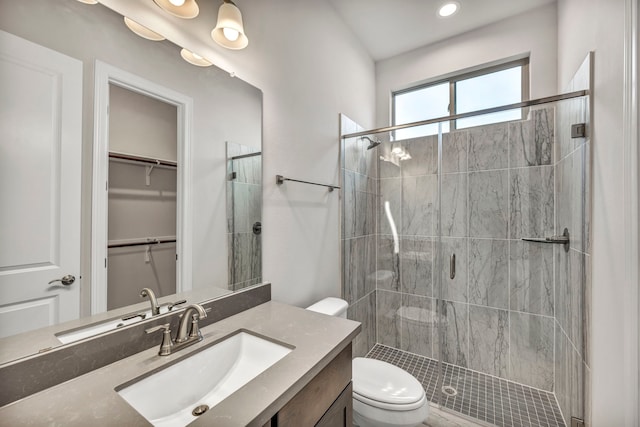 bathroom with toilet, vanity, and a shower with door