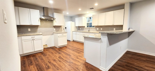 kitchen featuring tasteful backsplash, white fridge with ice dispenser, wall chimney range hood, white cabinets, and sink