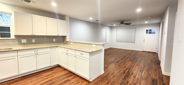 kitchen with white cabinetry, kitchen peninsula, ceiling fan, dark hardwood / wood-style floors, and light stone countertops