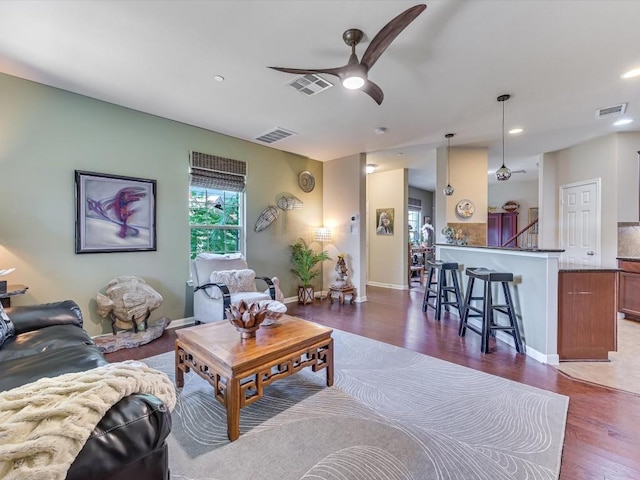 living room featuring dark wood-type flooring and ceiling fan