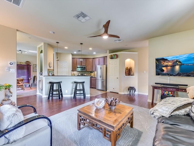 living room with dark wood-type flooring and ceiling fan