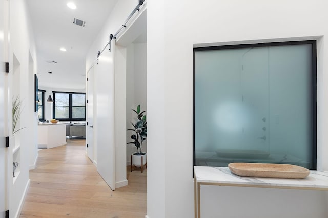 hall featuring a barn door and light hardwood / wood-style flooring